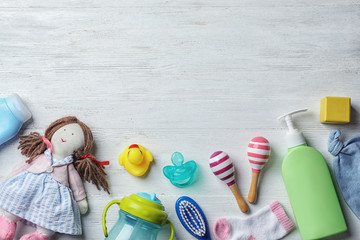 Flat lay composition with baby accessories and toys on light wooden background. Space for text
