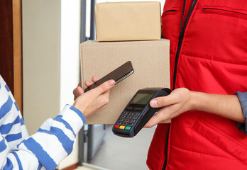 Woman with smartphone using terminal for delivery payment indoors, closeup