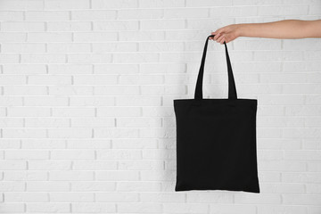 Woman holding eco bag near brick wall. Mock up for design