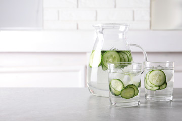 Glasses and jug of fresh cucumber water on table. Space for text