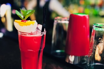Bloody Mary classic cocktails on bar . Close-up cold cocktail with crushed ice, mint and slice of lemon with on glass at dark background. Shaker and jigger barmen equipment.