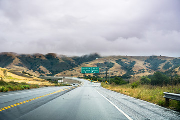 Driving on the highway through the hills of south San Francisco bay area on a cloudy day, California