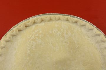 Close up of uncooked frozen apple pie on red background