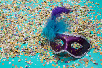 confetti spread on blue background with a female carnival mask