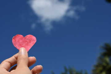 Hand with heart red over blue sky 