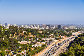 Fototapeta premium Aerial view towards the skyline of Westwood neighborhood; highway 405 with heavy traffic in the foreground; Los Angeles, California