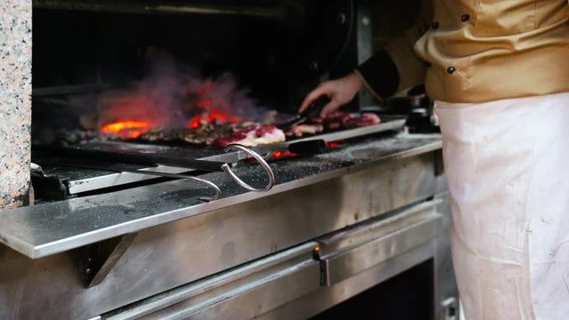 Grill, Frying Fresh Meat. Chef turns the meat on the fire flame.