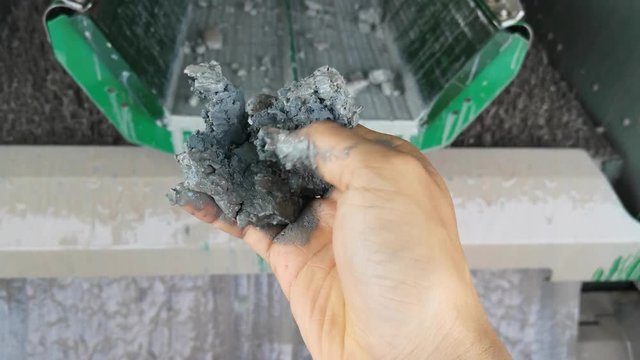 A hand squeezes cutting coming from a shale shaker on an offshore oil rig separating the cutting from water based mud