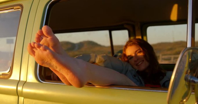 Woman legs out of the van window during sunset 4k