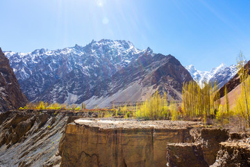 Beautiful autumn scene along Karakorum highway with layers of snow mountains and blue sky background