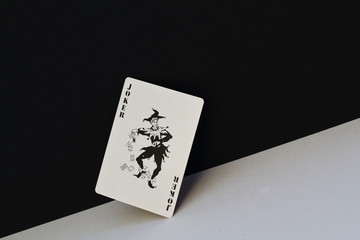 Unpredictable joker as symbol of opposites, contradictions of human nature. Black joker on contrasting white and black background.