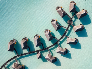 Luxury overwater villas with coconut palm trees, blue lagoon, white sandy beach at Bora Bora island, Tahiti, French Polynesia