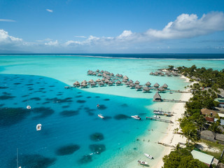 Luxusvillen über dem Wasser mit Kokospalmen, blauer Lagune, weißem Sandstrand auf der Insel Bora Bora, Tahiti, Französisch-Polynesien