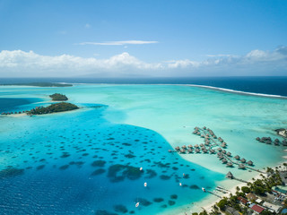 Luxury overwater villas with coconut palm trees, blue lagoon, white sandy beach at Bora Bora island, Tahiti, French Polynesia