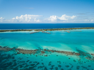 Luxury overwater villas with coconut palm trees, blue lagoon, white sandy beach at Bora Bora...