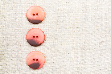 Large red sewn buttons on linen natural fabric 