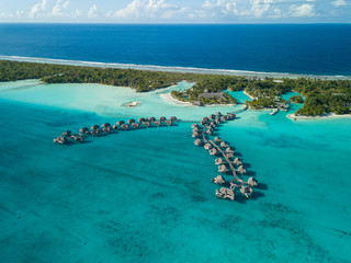 Fototapeta na wymiar Luxury overwater villas with coconut palm trees, blue lagoon, white sandy beach at Bora Bora island, Tahiti, French Polynesia