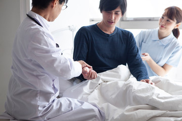 入院患者のベッドで脈拍を確認する医師