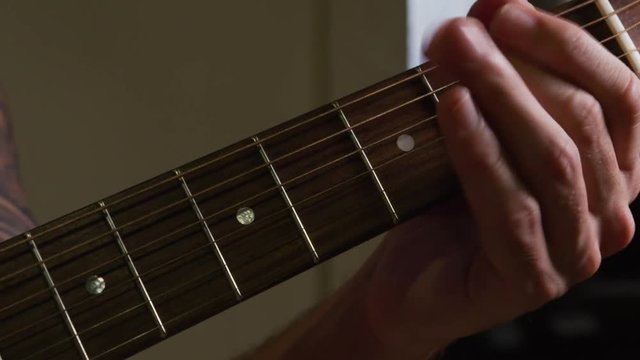 A man softly plays his guitar.