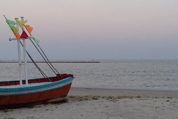 Fototapeta premium Red Fishing Boat with colorful flag parked at one of the beaches in the morning.To be a tsunami warning signal.