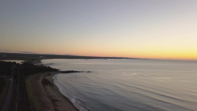Aerial view of a Beautiful Sandy Beach on the Atlantic Ocean Coast during a vibrant sunrise. Taken near in Pabos Mills, Quebec, Canada.