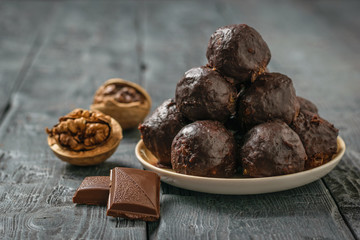 Chocolate-drenched balls of grated nuts and dried fruits in a bowl on a wooden table.