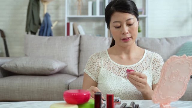 Beautiful asian woman blogger is showing cosmetics products introducing on internet online shop. young girl teaching make up in front of camera to recording vlog video live streaming at home.