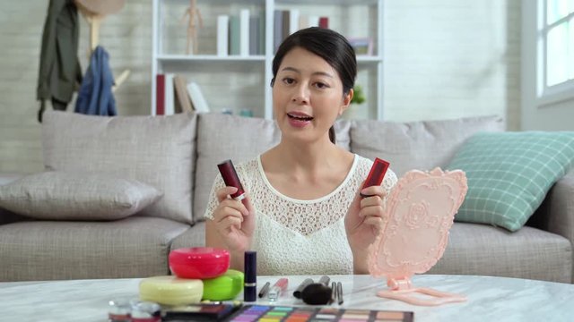 Asian young female blogger recording vlog video with makeup cosmetic at home online influencer on social media concept. famous beautiful vlogger introducing lipsticks in live streaming viral.