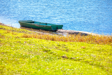 old wooden boat on the green river shore