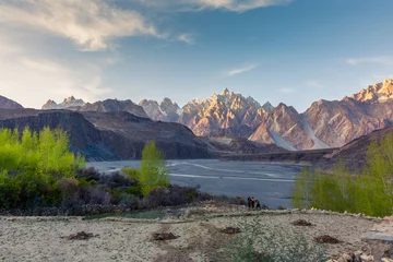 Papier Peint photo Gasherbrum Tupopdan mountain also known as Passu Cones or Passu Cathedral, big rocks all over the place and blue crystal of Hunza river at sunset time ,Northern of Pakistan