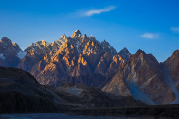 Montagne Tupopdan également connue sous le nom de Passu Cones ou Cathédrale de Passu, gros rochers partout et cristal bleu de la rivière Hunza au coucher du soleil, nord du Pakistan