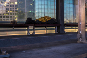 homeless person asleep next to freeway