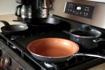 Modern stainless steel gas stove oven in a home with various cookware.
