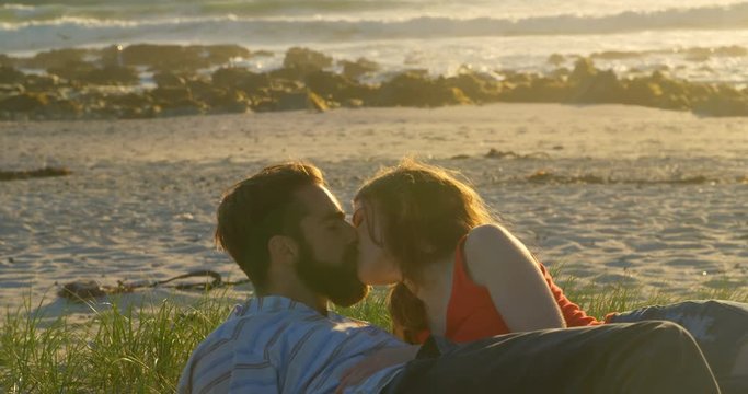 Beautiful romantic couple lying down and kissing on the beach 4k