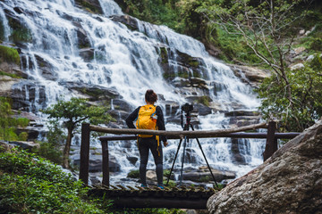 Obraz premium Asian woman travel relax to photograph the waterfalls beautiful. In the winter. at the waterfall mae ya chiangmai in thailand. travel nature. summer