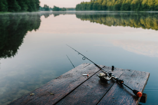 Fishing rod, spoon, hooks on a brown wooden background. fishing bait. close up. throw-line. fishing rod. Rod on the bridge. Bridge passes through the lake, river. flat lay. top view.