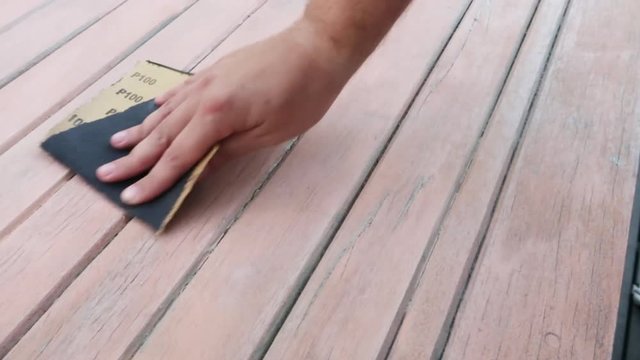 close up footage of a male hand using sand paper to sand a wooden door or table