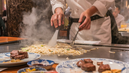Cooking vegetables on a hot grill in Japanese steakhouse with scraper