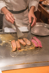 Vertical photo of Japanese chef cooking Kobe beef in the restaurant