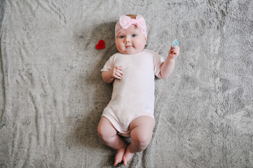 Little girl baby playing with toys, the baby lies on warm gray plaid, infant lying on the...