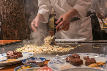 Chef cooking stir fried bean sprout with beef steaks with scraper