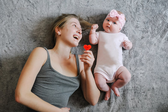 Happy mother and daughter. A little girl, the baby, newborn, mom lies on the background bed, playing with toys. Photo shoot 4-5 months. flat lay. top view.