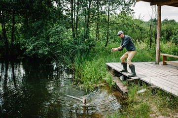 Fototapeta na wymiar Fisherman with fishing rod caught a big fish pike out of water on bridge, pier. Good catch. Trophy fish. angler. Fishing background, grass, trees against the backdrop of lakes, river. wild nature.
