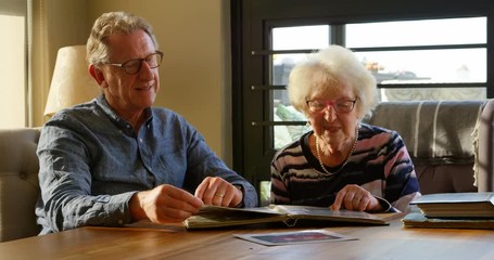 Active senior couple looking at photo album 4k - Powered by Adobe