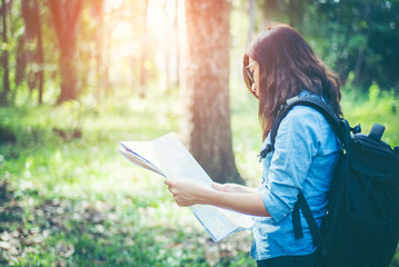 Obraz premium In tropical forest. Asian girls hikers She is holding a map and analysis of travel plans within the forest amid the hot weather and afternoon sun with copy space.