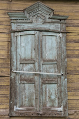 Antique wooden window of a village house closed against a wooden wall