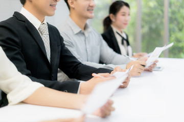 Fototapeta premium Cheerful business man sitting with other professionals waiting for job interview. Group of people waiting for job interview in office.
