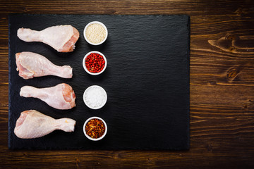 Raw chicken drumsticks on wooden background