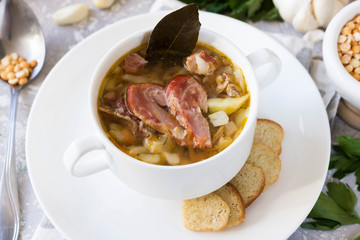 Thick pea soup with smoked meats in a white plate