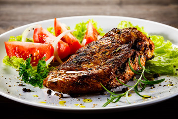 Grilled chicken fillet and vegetables on wooden background